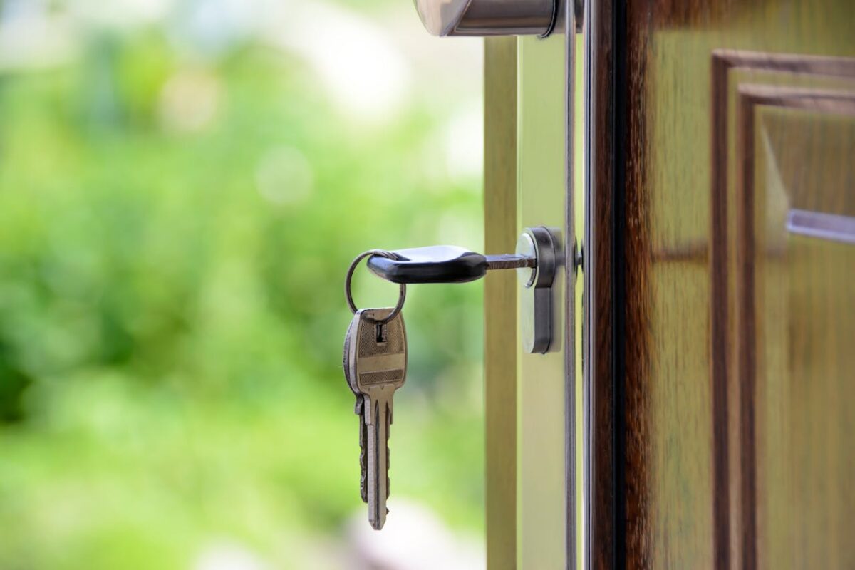 services-03 Key inserted in door lock against a blurred green background, symbolizing security and real estate.