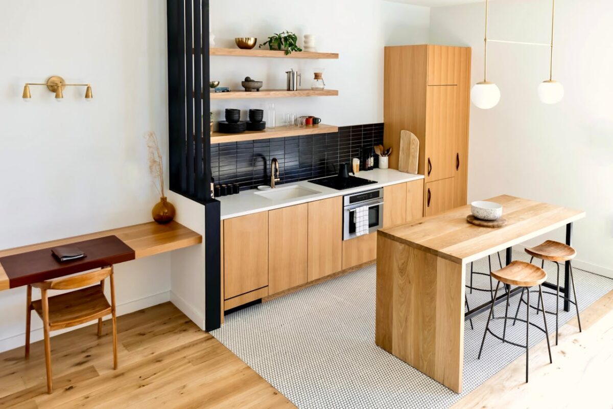 services-01 Light-filled modern kitchen interior with wooden furnishings and black accents.